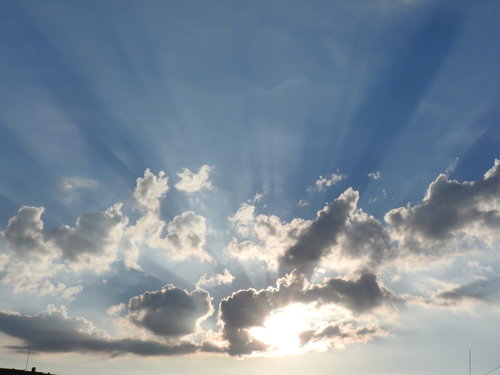 空に広がる夕陽の光芒と雲のグラデーション