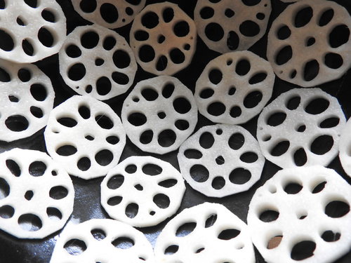 白い背景に規則正しく並べられたレンコンの輪切り