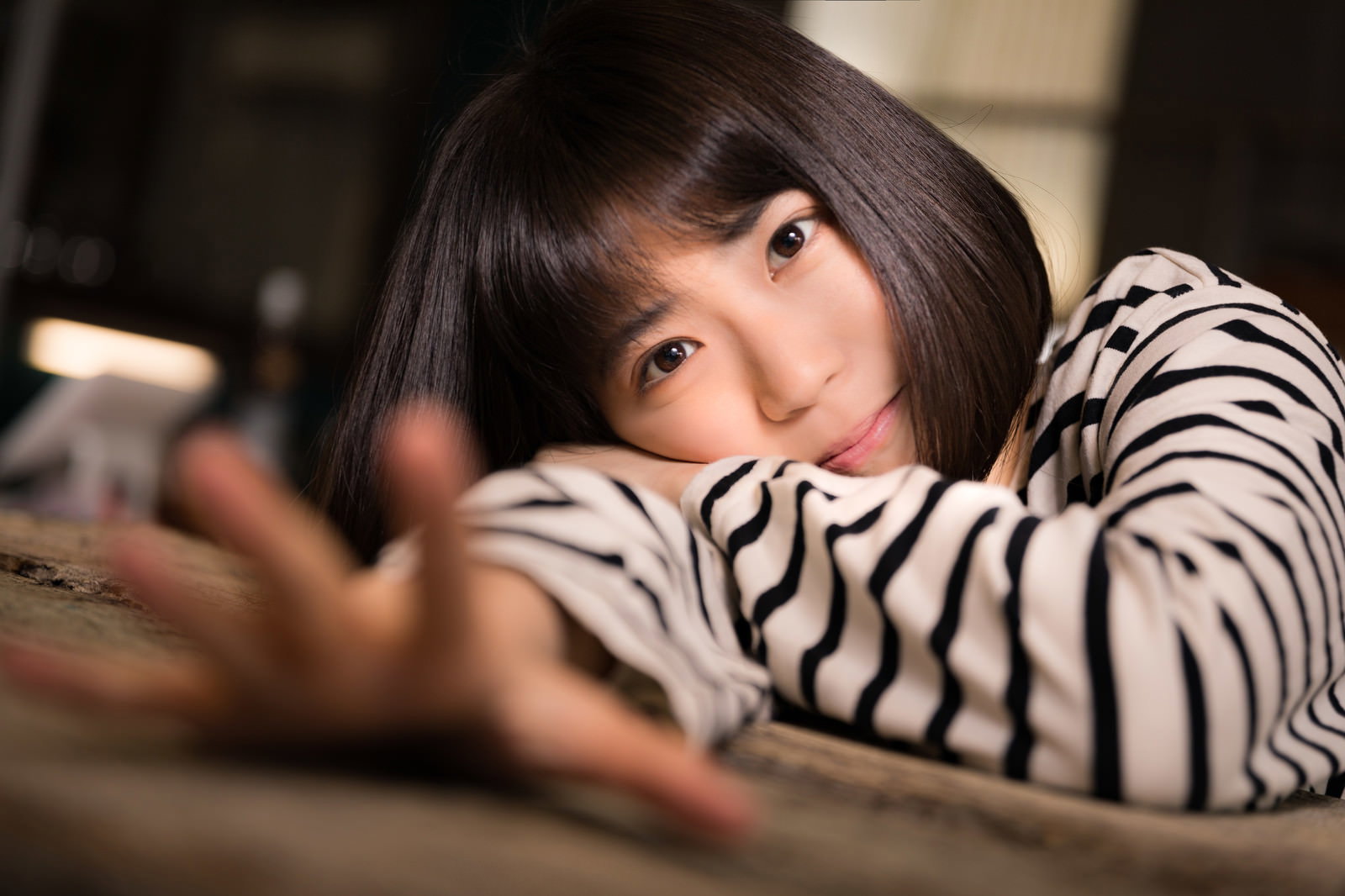 カフェでカップを持つボーダー服の女性［モデル：塩田みう］