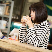 挽きたてのコーヒーを飲むカフェでくつろぐ女性の写真