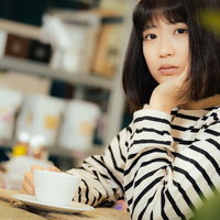 カフェでボーダー柄の服を着て退屈そうにこちらを見つめる女性の写真