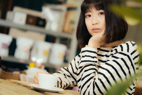 カフェでボーダー柄の服を着て退屈そうにこちらを見つめる女性