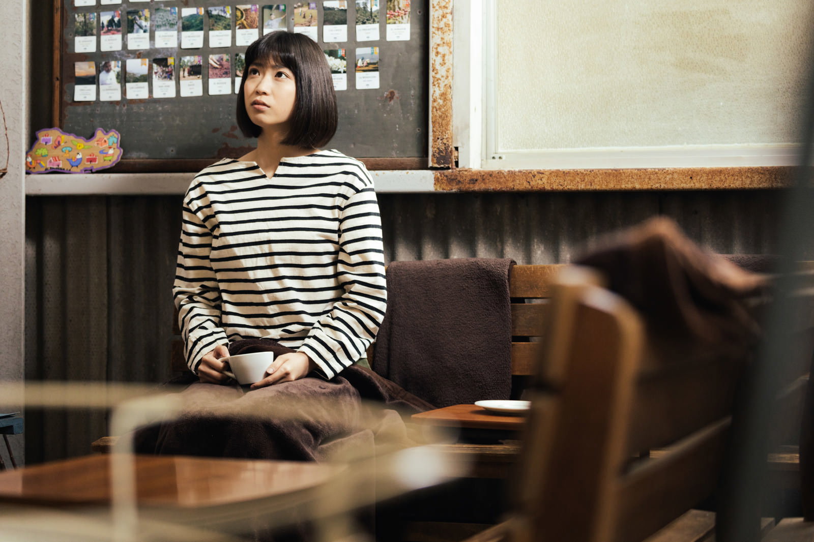 レトロなカフェの木製テーブルでコーヒーを楽しむボーダーシャツの女性［モデル：塩田みう］