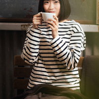 ボーダートップスを着てコーヒーで温まる女性の写真
