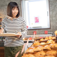 パン屋で今日は何のパンを食べようかなぁと選ぶ女性の写真