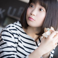 フードコートでパンを食べながらスマホを見る女性の写真