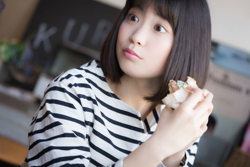 フードコートでパンを食べながらスマホを見る女性