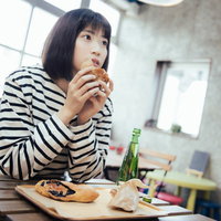 フードコートで菓子パンをほおばる女性の写真