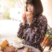 自然光に包まれたカフェでティータイムを楽しむ女性の写真