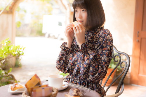 自然光に包まれたカフェでティータイムを楽しむ女性