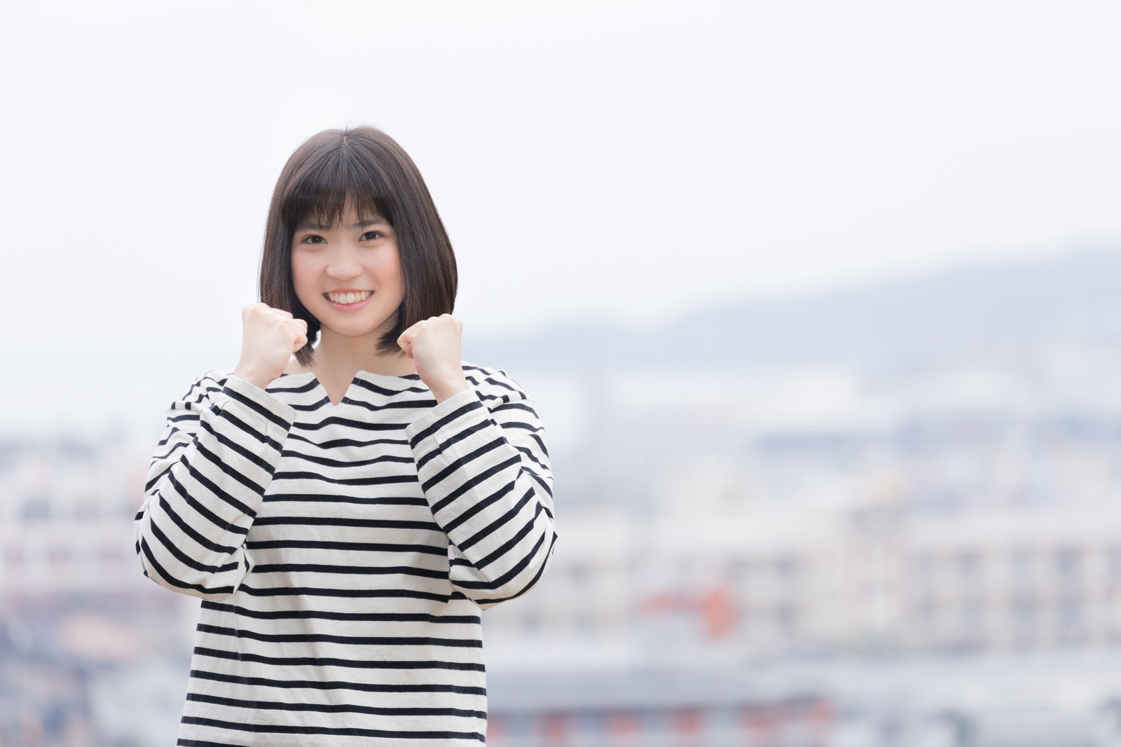 ボーダーシャツを着た女性がガッツポーズで応援している様子［モデル：塩田みう］