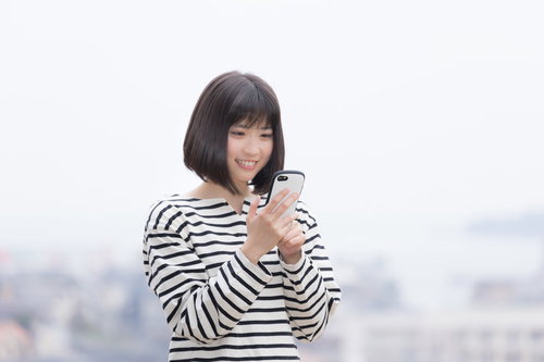スマホで簡単登録する笑顔の女性のスマートフォン操作