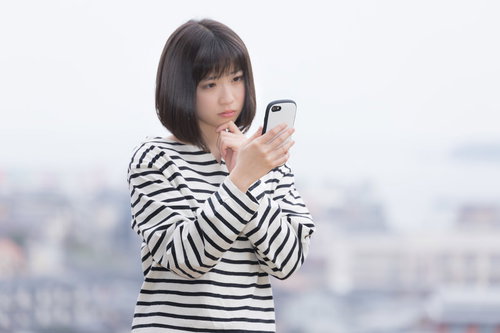 電波がなくてネットに繋がらないスマホを見つめる女性