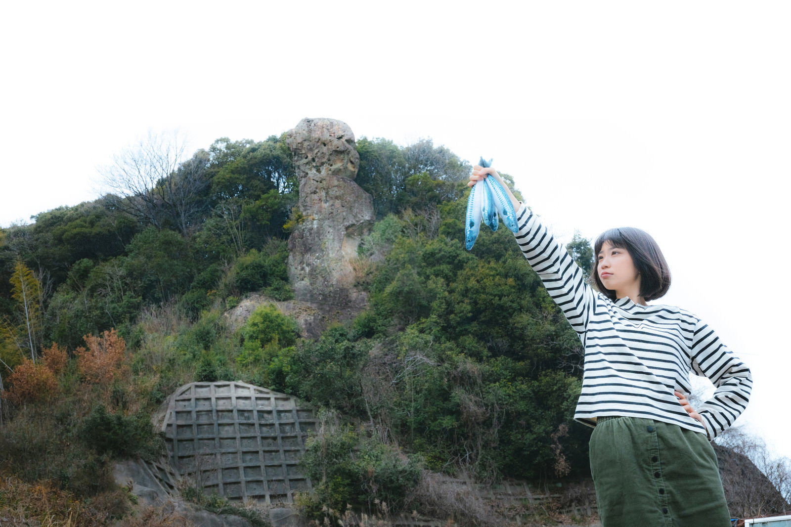 長崎県時津町の鯖くさらかし岩を背景に立つボーダーシャツの女性［モデル：塩田みう］