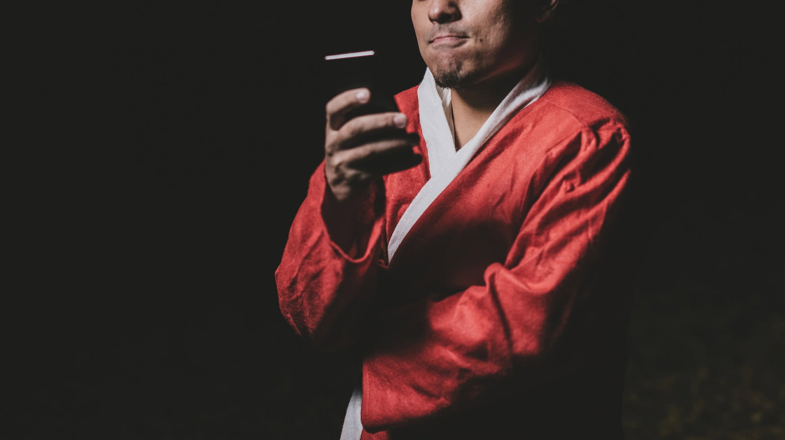 赤いサンタコスプレを着た男性がスマートフォンでフリマアプリを操作している様子