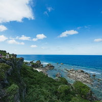 緑豊かな崖の上から望む沖縄宮古島の青い海と夏空の写真