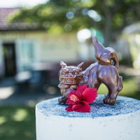 宮古島の狛犬の置物と赤いハイビスカス、沖縄文化の象徴の写真