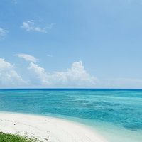 宮古島の白い砂浜から望む水平線とエメラルドグリーンの海の写真