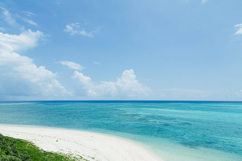 宮古島の白い砂浜から望む水平線とエメラルドグリーンの海