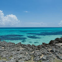 宮古島の海岸から見たエメラルドグリーンの海と水平線、積乱雲の写真