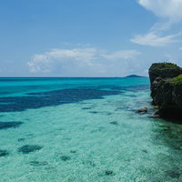 宮古島の岩場から見下ろす透明度の高いエメラルドブルーの海岸線の写真