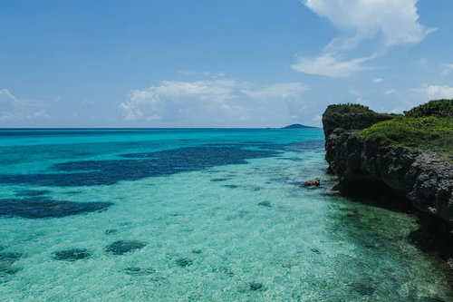 宮古島の岩場から見下ろす透明度の高いエメラルドブルーの海岸線の写真