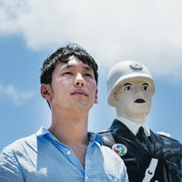 宮古島の宮古まもる君と青空を見つめる男性の写真