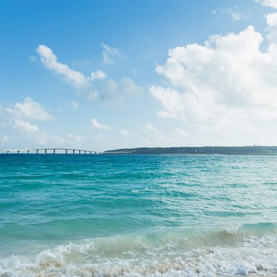遠景に伊良部大橋が見える宮古島のエメラルドグリーンの海の写真