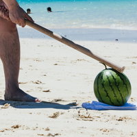 海辺でスイカ割り！テイッと棒を振る女性の足元の写真