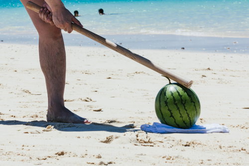 海辺でスイカ割り！テイッと棒を振る女性の足元