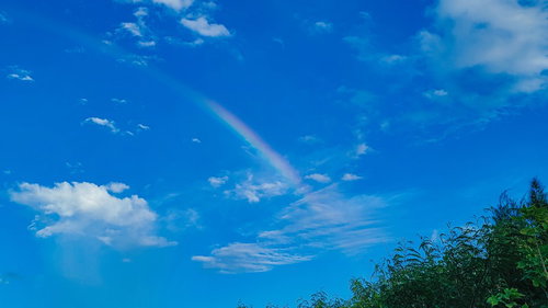 宮古島の青空に架かる虹と白い雲