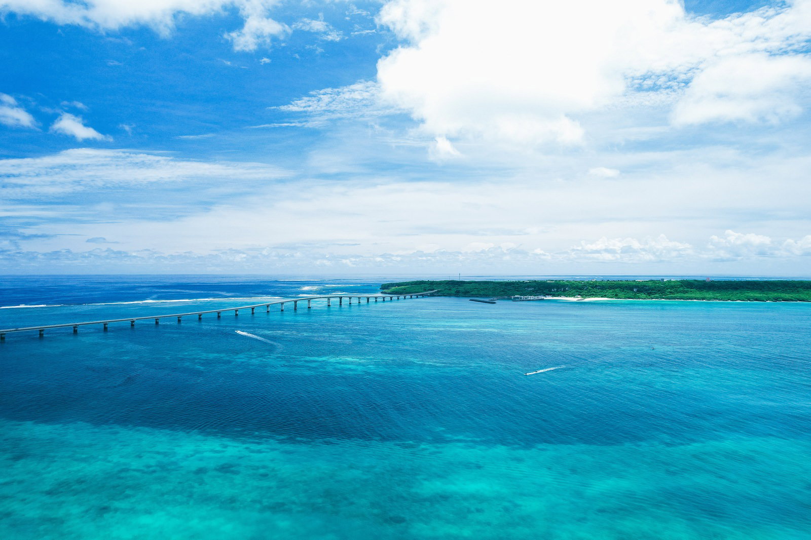 空撮した来間大橋とサンゴ礁の青い海