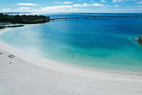 白い砂浜から見える伊良部大橋と透き通ったエメラルドグリーンの海