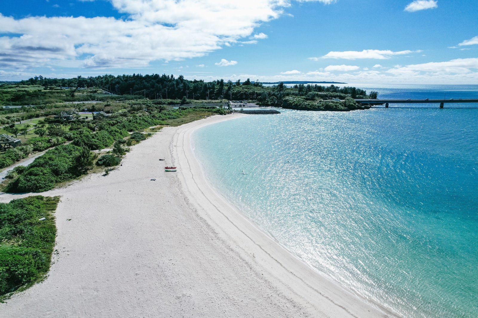 Crescent-shaped white sand beach and transparent emerald blue sea along the coast of Miyakojima, Japan