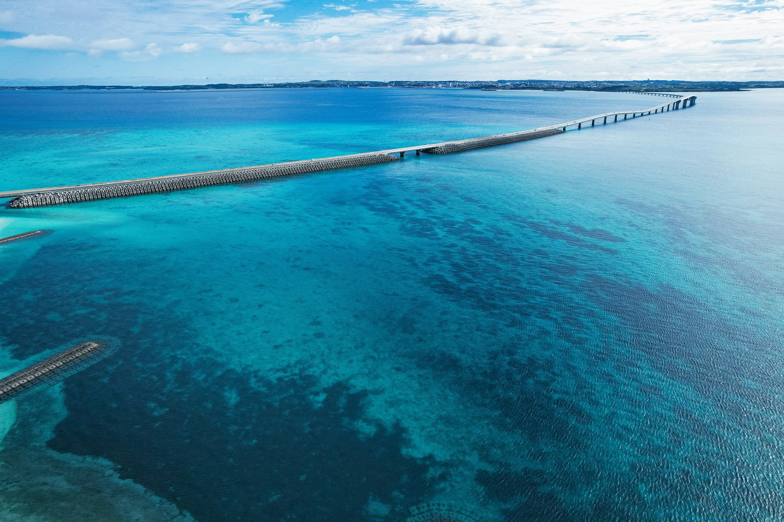 エメラルドグリーンの海の上を一直線に延びる伊良部大橋の空撮写真