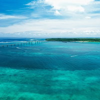 伊良部大橋の向こうに見えるエメラルドグリーンの海と水平線の写真