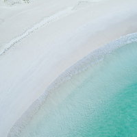 宮古島の白い海岸に寄せるエメラルドグリーンの波の写真