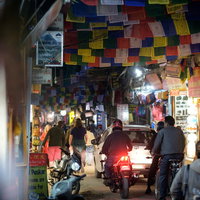 人でごった返す細い商店街に車とバイクが侵入する光景（ネパール）の写真