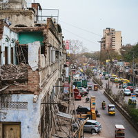 ニューデリーの倒壊しそうな建物と交通量の多い大通りの写真