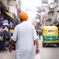 ニューデリーの商店街でオレンジ色のターバンを巻いた人の後ろ姿の写真
