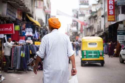 ニューデリーの商店街でオレンジ色のターバンを巻いた人の後ろ姿