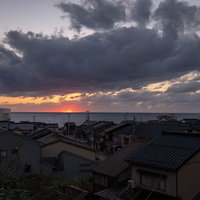 沈む夕日と海沿いの民家の風景 - 夕焼けに染まる住宅街の写真