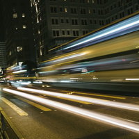 夜間の都会を走る自動車の光跡の写真