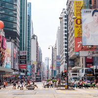 香港の高層ビル群が立ち並ぶ都市部で横断する人々の写真