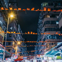 夜間に香港旗が連なって吊るされた繁華街の商店街の写真