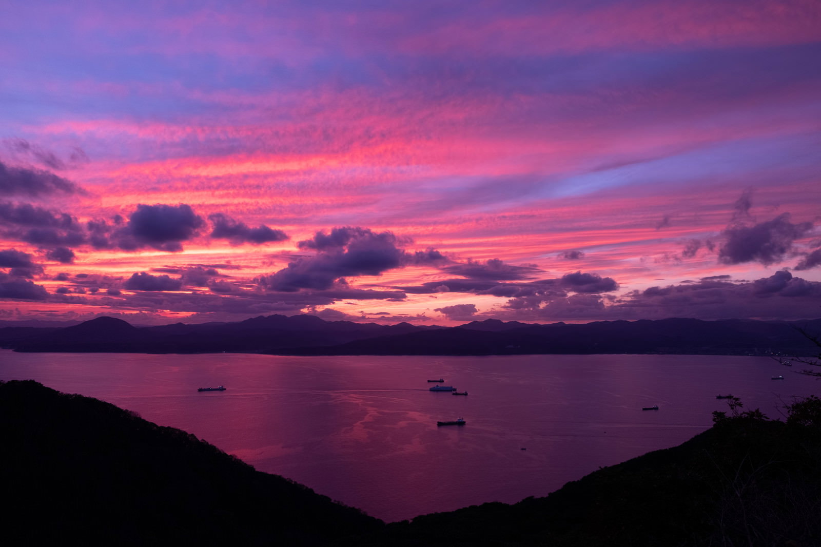 夕焼けの湾に浮かぶ船のシルエット