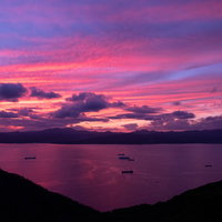 紫とピンクに染まる夕暮れの湖とシルエットの写真