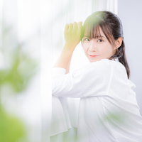 窓に寄り掛かり髪に手をやる白シャツの女性ポートレートの写真