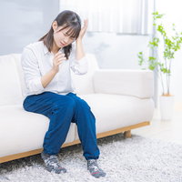 群発頭痛で何度も頭を抱える女性のストレスと疲労の写真