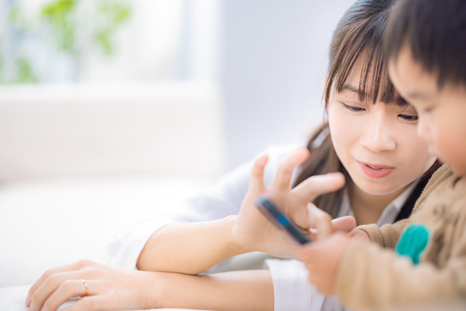 スマートフォンを操作する母親と子供［モデル：本坊実結］